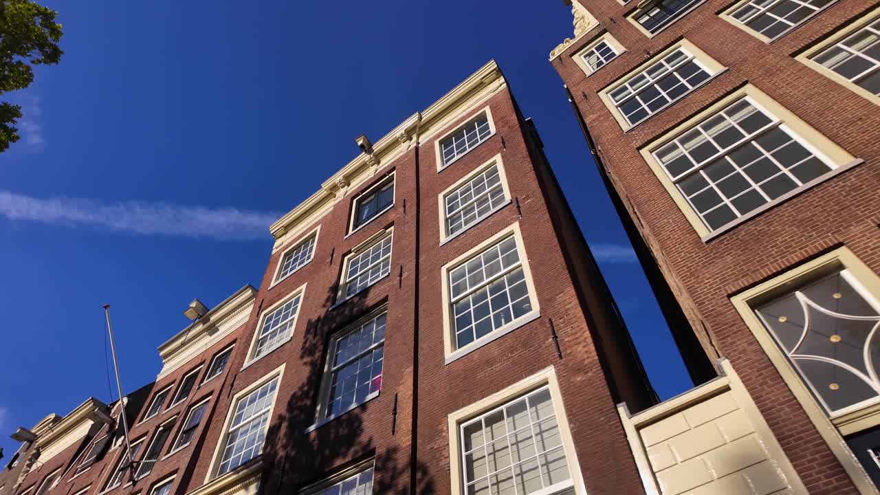 Upward view of Amsterdam canal houses with large windows and blue sky reflections on a sunny morning. Location: Amsterdam, Noord-Holland, Netherlands (Amsterdam, Noord-Holland, Nederland)