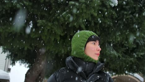 Schöne-Frau-Dreht-Ihren-Kopf-Vor-Dem-Hintergrund-Von-Bäumen,-Von-Denen-Schmelzender-Schnee-Fällt,-Zeitlupenaufnahmen