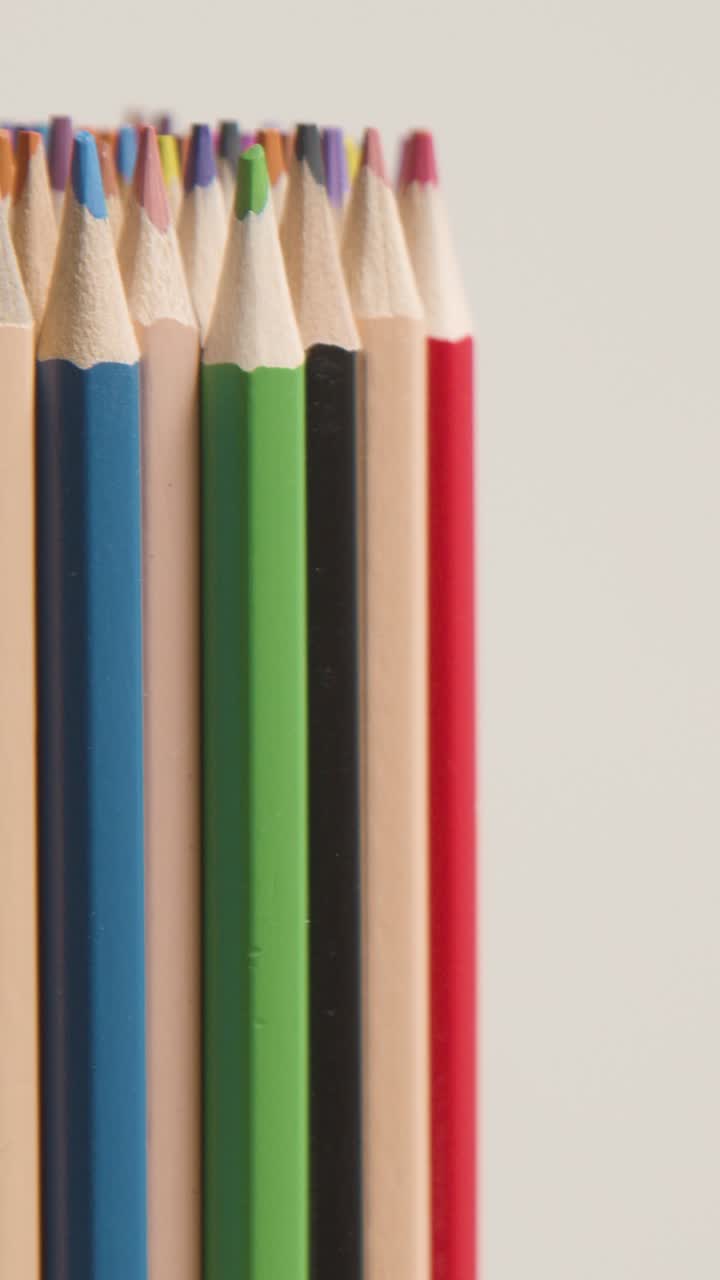 백색 바탕에 회전하는 다채로운 연필의 수직 비디오 스튜디오