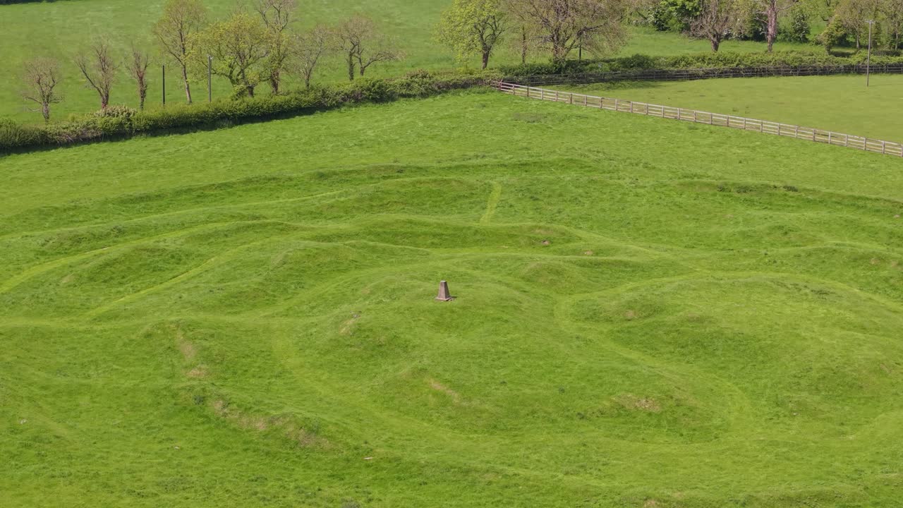 Green grassy hill with earthen ringfort ruins in County Meath, Ireland