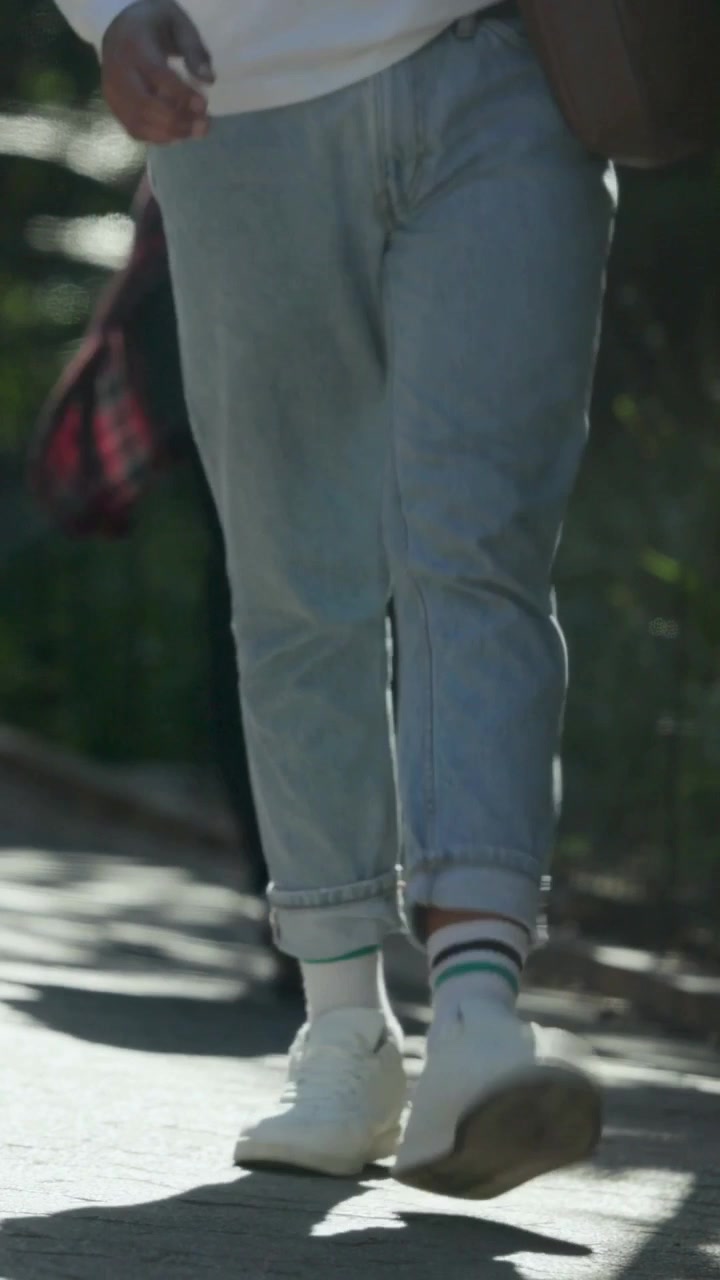 Video verticale: Donna con leggings rossi e scarpe bianche che si allontana camminando, mentre la telecamera inizia a riprendere sul sentiero.