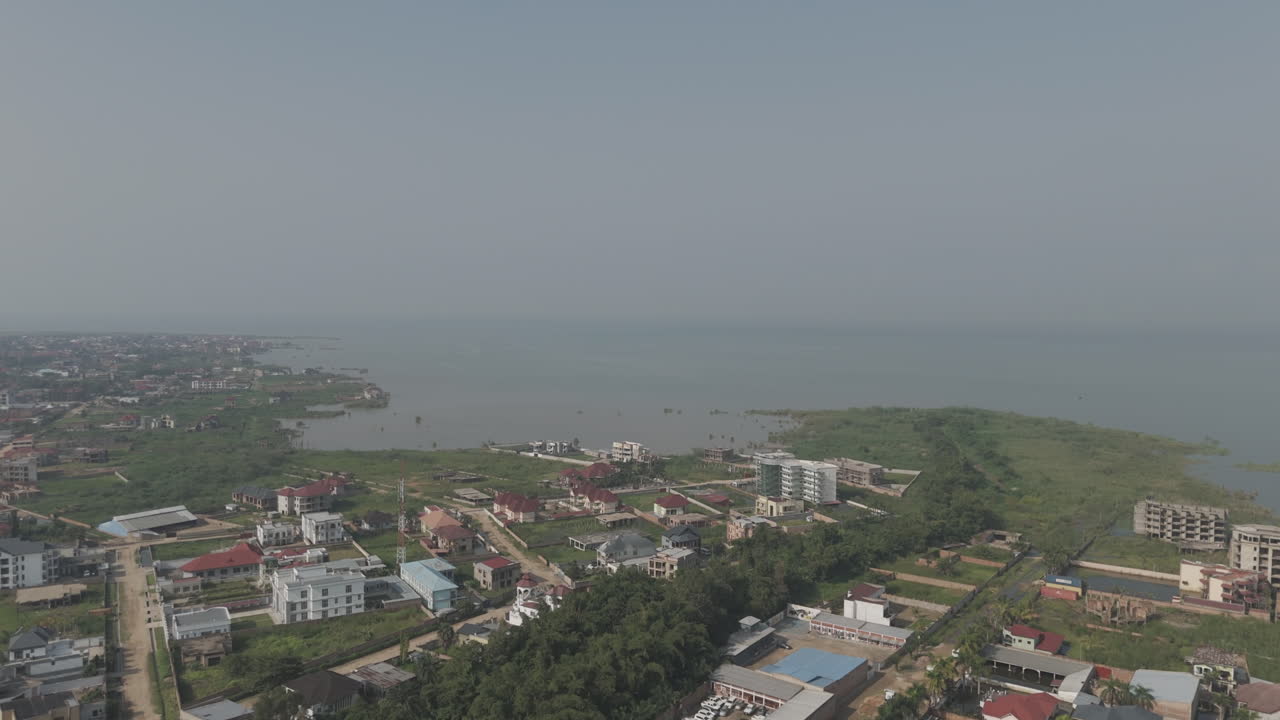 Sideways flying drone shot above Bujumbura Burundi Africa looking over the houses and lake Tanganyika with mist and pollution in the air LOG