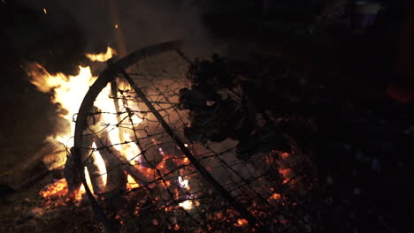 nighttime argentine asado with a roaring fire cooking an abundance of meat - slow motion