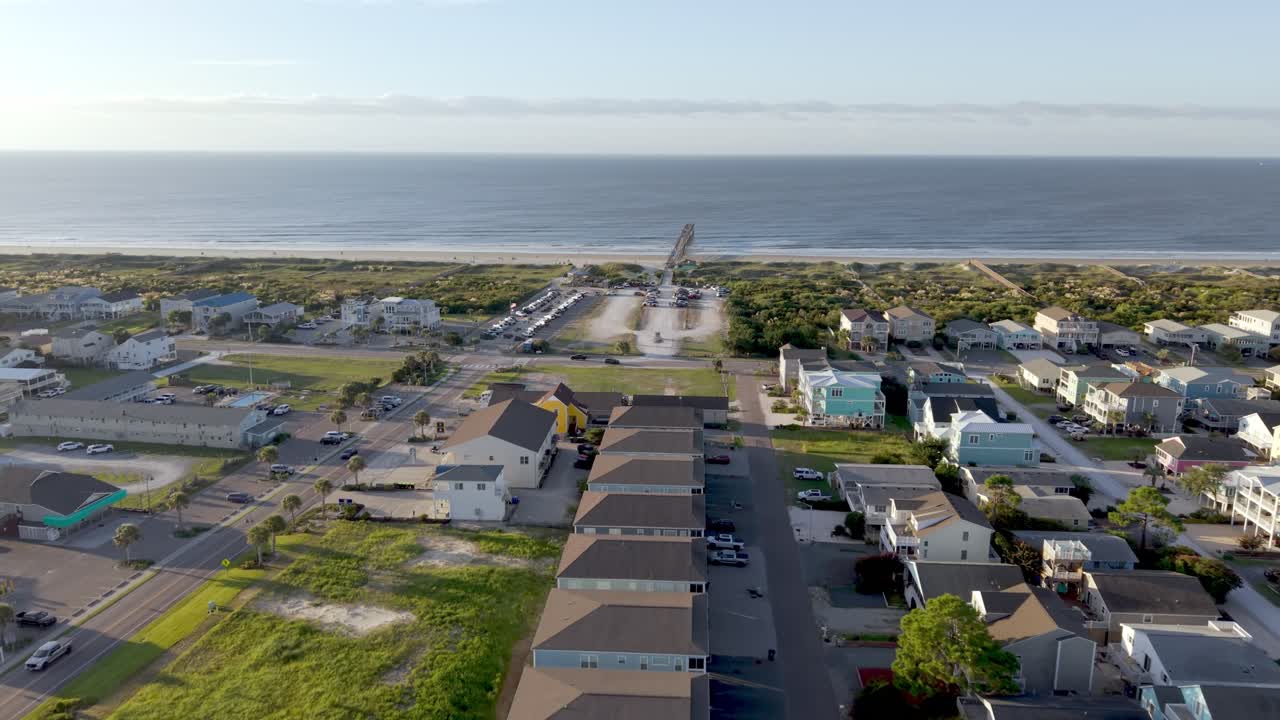 Aerial push in to homes and beachfront pier sunset beach nc, north carolina