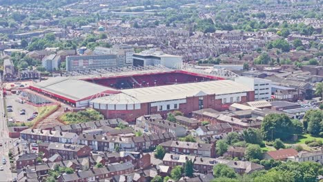 a large stadium surrounded by a densely packed residential area with numerous buildings and greenery is shot from above. the well-organized urban landscape showcases a blend of architecture and nature