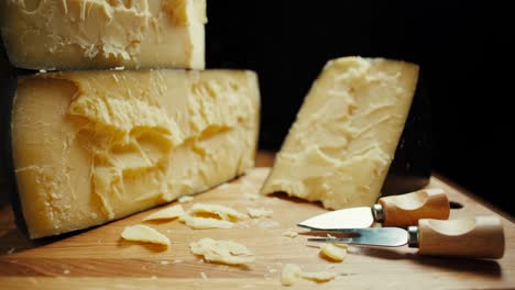 medium hard cheese head parmesan on wooden board, with cheese parmesan knifes. slide shot