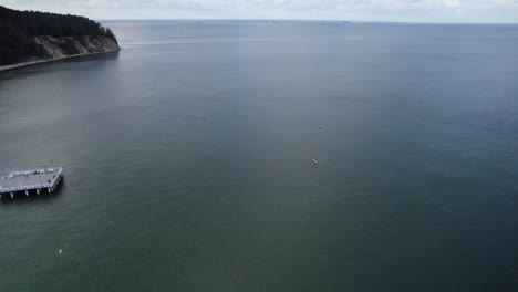 Aerial-distant-view-of-people-Paddle-Boarding-in-Baltic-sea-by-the-cost-of-Gdynia-city-on-cloudy-summer-day