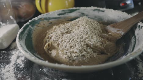 adding oats to cookie mixture in a bowl - close up