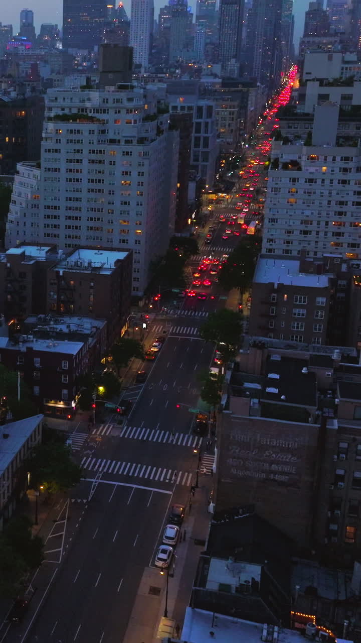 Lots of cars with red lights on in the streets of evening New York. Metropolis cityscape at dusk time. Beautiful skyscrapers at backdrop. Vertical video