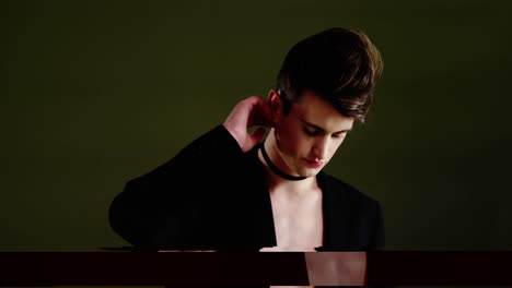 Androgynous-man-in-blazer-posing-against-black-background