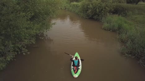 Hombre-En-Kayak-En-El-Río-Serpenteante-Con-Juncos-Arbustos-Y-árboles-En-Ambas-Orillas