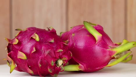 two dragon fruits rotating on a wooden table