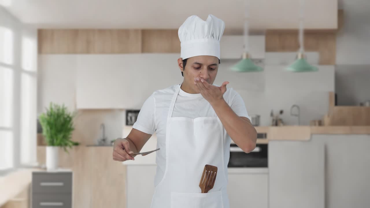 Felice chef professionista indiano che assaggia il cibo e mostra il segno dell'okay.