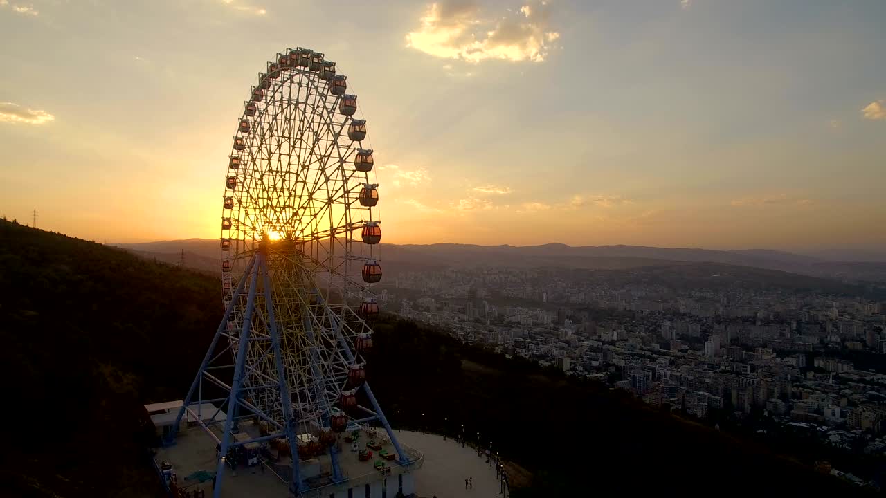 산과 도시의 공중 파노라마 뷰에 있는 놀이 공원의 페리스
