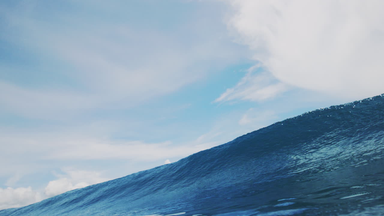 깊은 파란 빛나는 바다 물은 구름이 가득한 하늘 아래에서 깨지는 것처럼 질감이 있습니다.