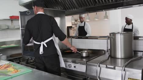 focused diverse male chef instructing trainee male chefs in kitchen, slow motion