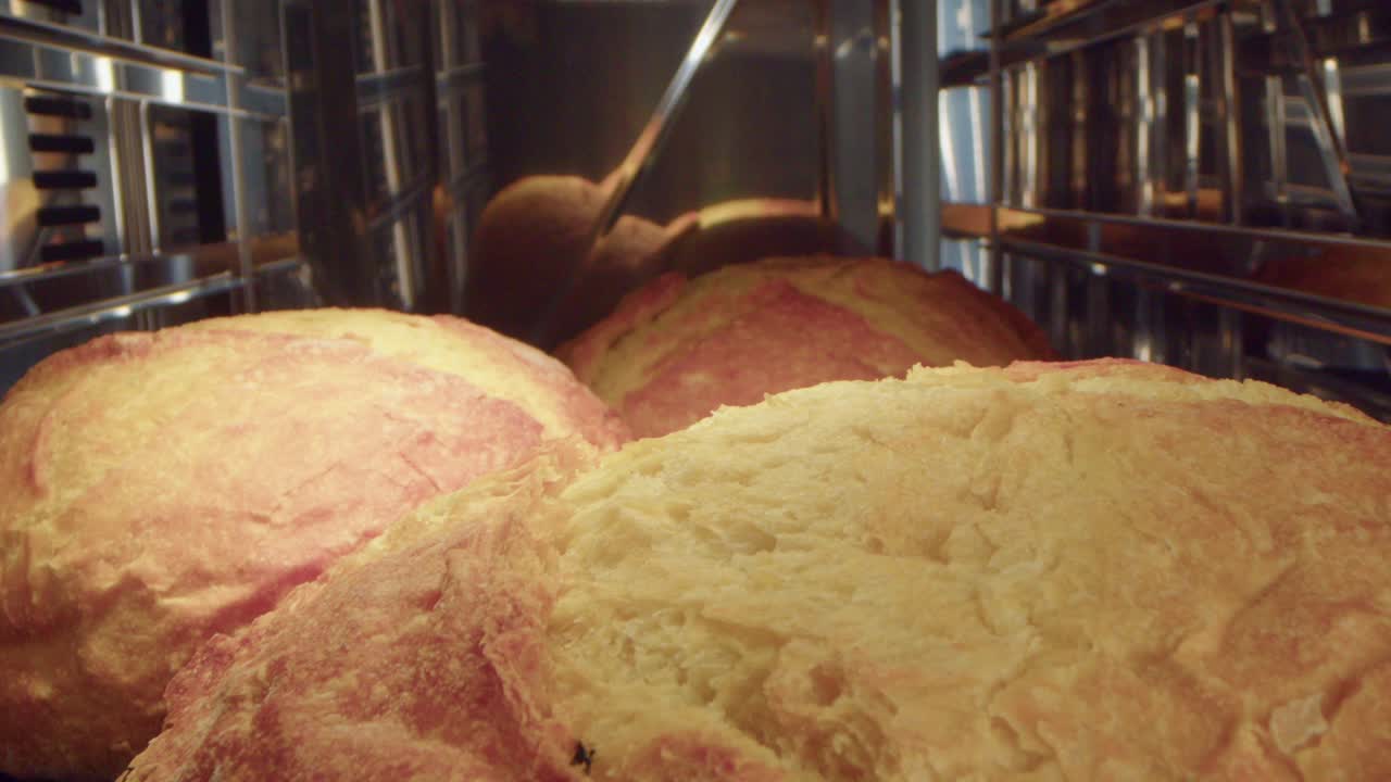Camera pulls back to closeup view of freshly baked golden brown crust crisps bread in oven.