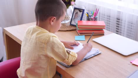 small boy writing something in copybook