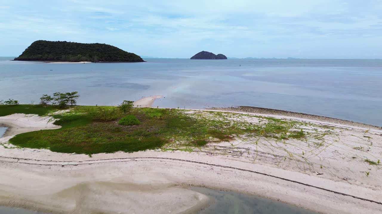 Drone video shows traditional small fishing boats anchored near the sandy shoreline of Koh Phangan, Thailand, with clear turquoise water and lush green coastline creating a scenic tropical seascape
