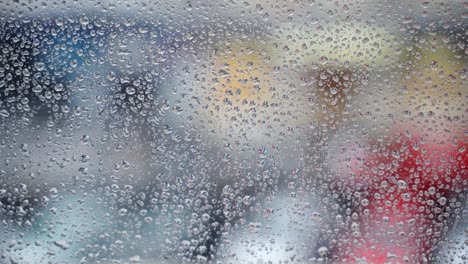 wet window surface after heavy raining, droplets on window glass on blurred cloudy street traffic background. cinematic shot of raindrops, wallpaper pattern with copy space