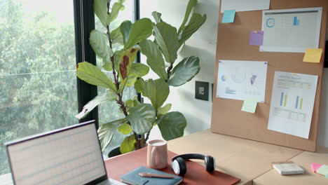 working from home, laptop, notebook, and headphones on desk with plant nearby