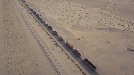 Long-line-of-trucks-in-the-desert-waiting-–-slow-pan-down