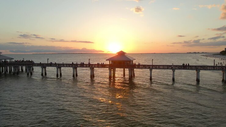 People looking to a beautiful sunset over the ocean in Fort Myers Pier, Florida