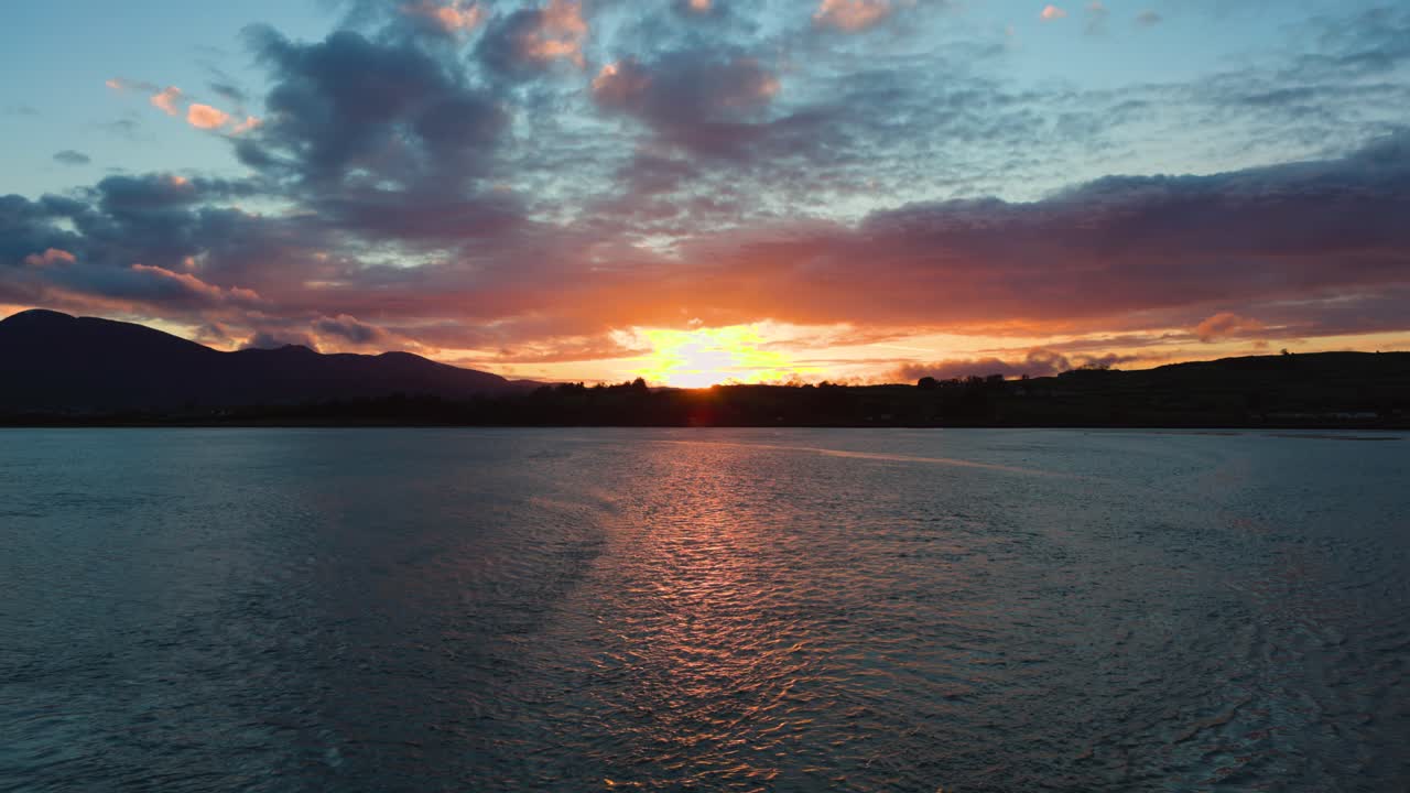 Tranquil Coastal Sunset with Mourne Mountains Silhouetted Against a Glowing Sky