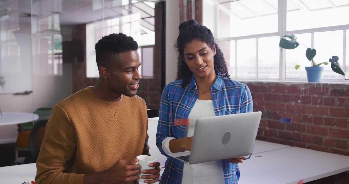Woman angling laptop, man leaning, tapping, pointing, UI badges floating, rising during tech review