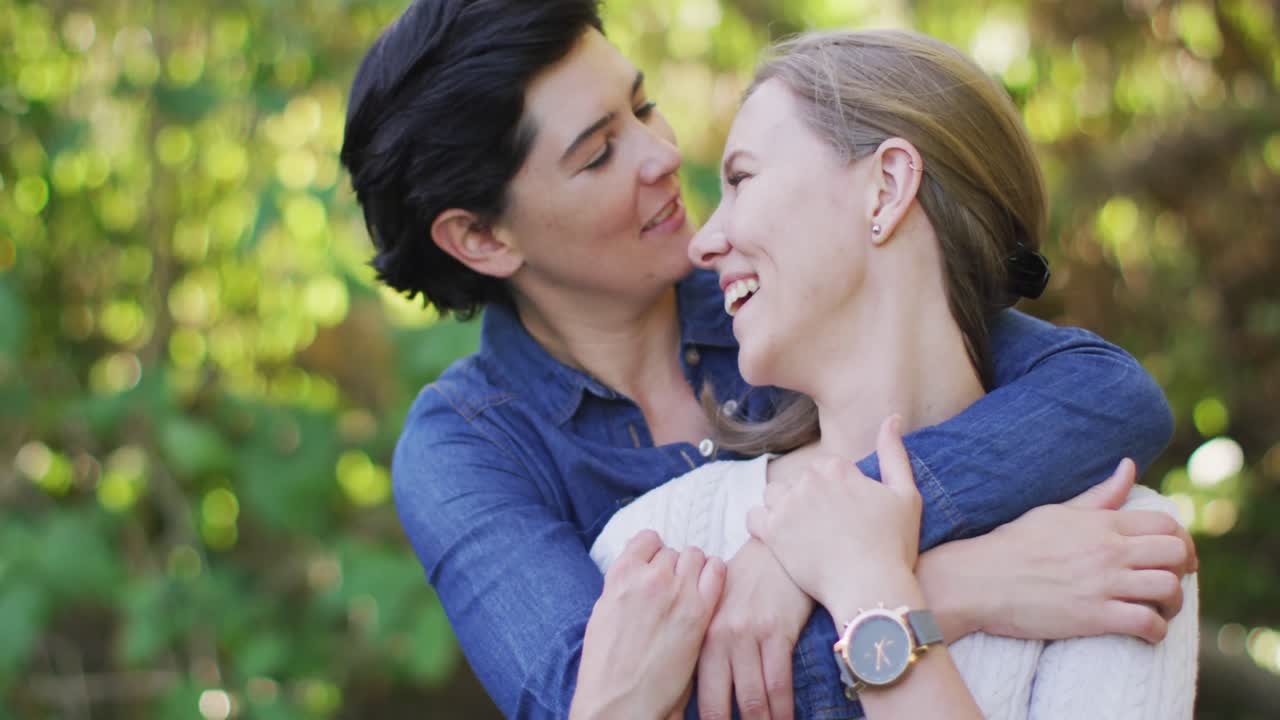 feliz pareja de lesbianas caucásicas abrazándose en el jardín