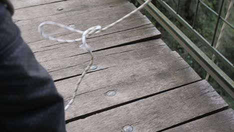 detail shot of safety rope unraveling while firefighter descends from bridge, slowmo