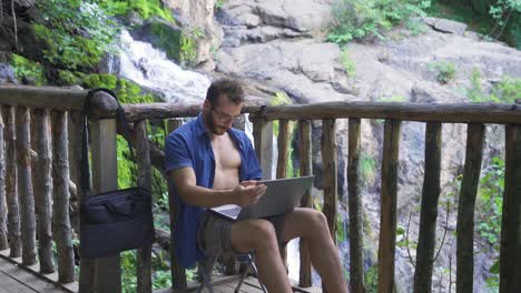 office worker working outdoors in forest with waterfall.