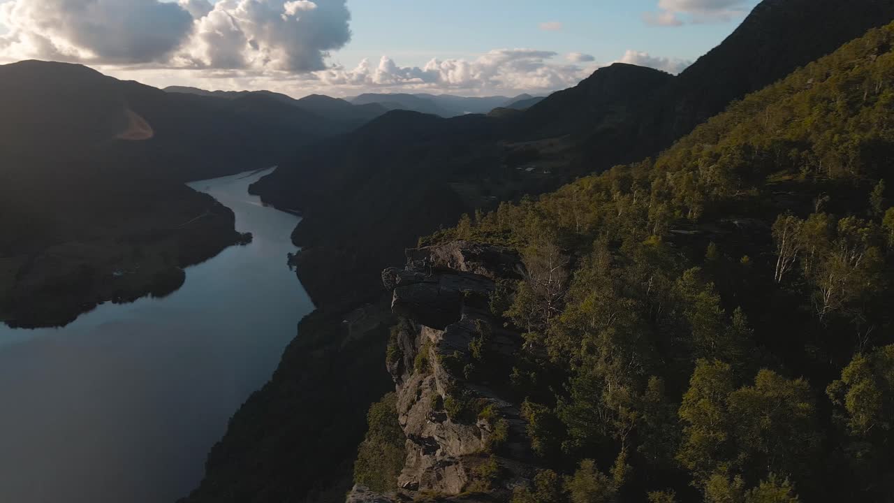 Turyści stoją na wystającej skale i obserwują majestatyczny norweski fiord z górskiego klifu.