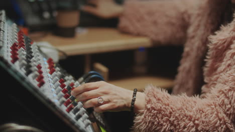 female music producer using mixing console in recording studio