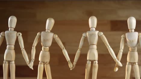 wooden figurines representing businesspeople holding hands