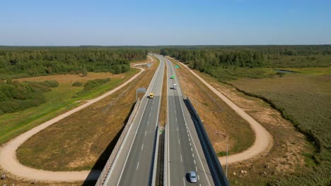 cargo trucks driving on the highway through forested landscape, elk river in view, aerial view