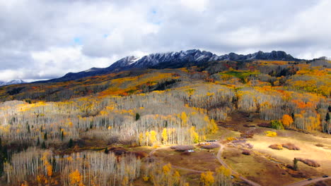 dramatic autumn aspen tree fall colors kebler pass trailhead aerial cinematic drone snow on peaks landscape crested butte gunnison colorado early fall red yellow orange rocky mountains upward circle