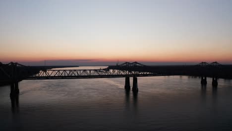 low aerial shot flying over the natchez-vidalia bridge on the mississippi river at sunset