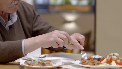 senior man having dinner in restaurant, close-up