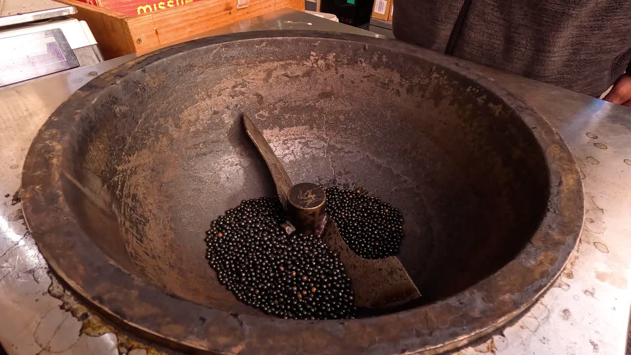 Person adds stones to stove for roasting chestnuts