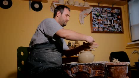 professional potter shaping pot with special tool in pottery workshop