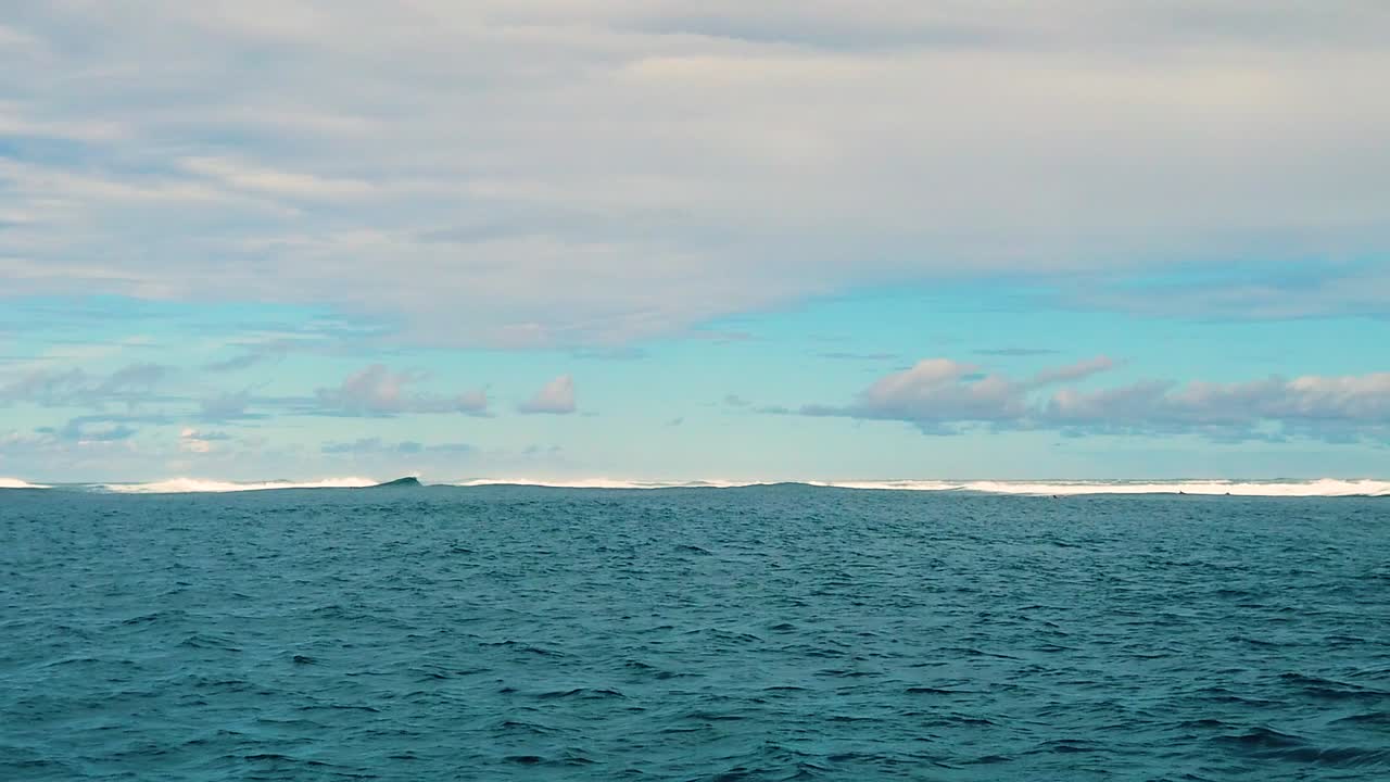 hd 120fps 하와이 카우아이 바다에서 보트 타기 왼쪽에서 오른쪽 서퍼가 거리에서 파도를 기다립니다