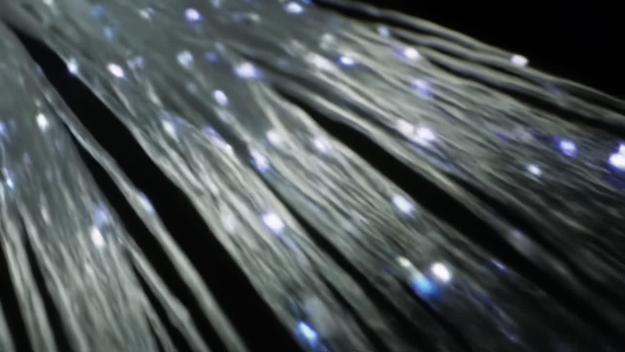 Illuminated strands of light cascade in a dark setting, creating a captivating visual experience. The glowing points of light twinkle and shimmer, adding enchanting effects.