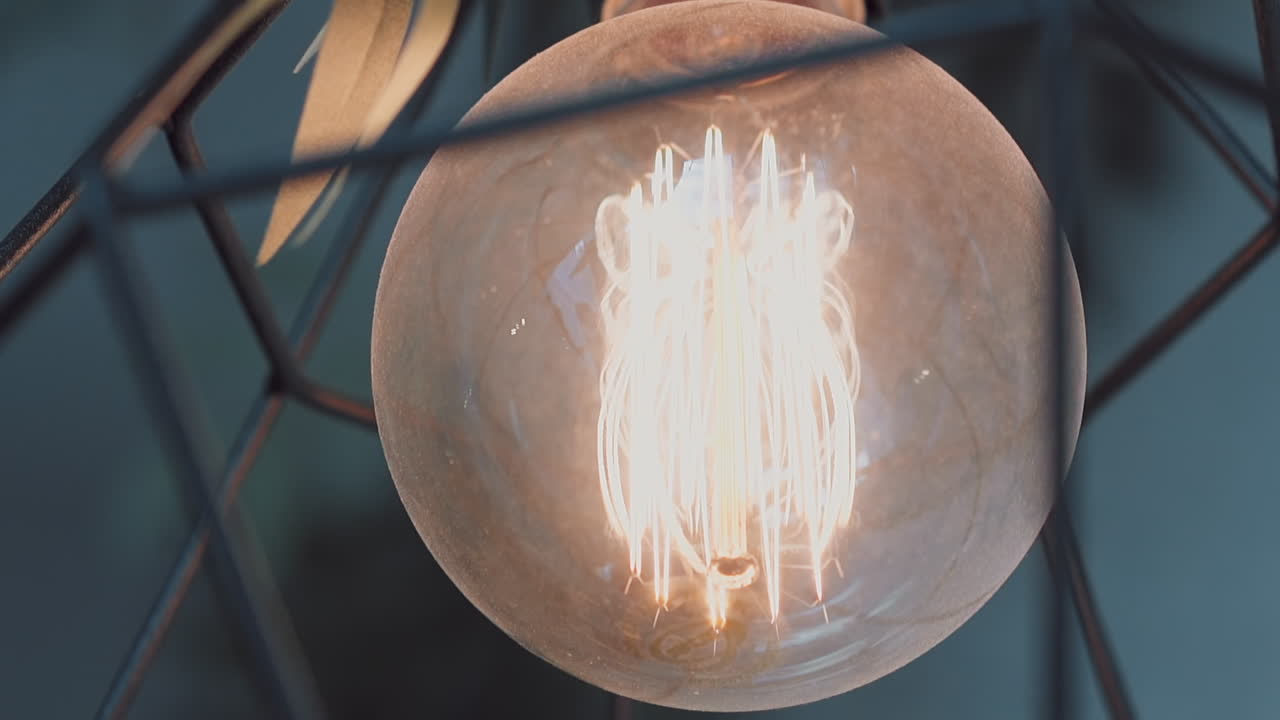 금속 사체와 함께 빛나는 전구 내부의 나선형 필라멘트