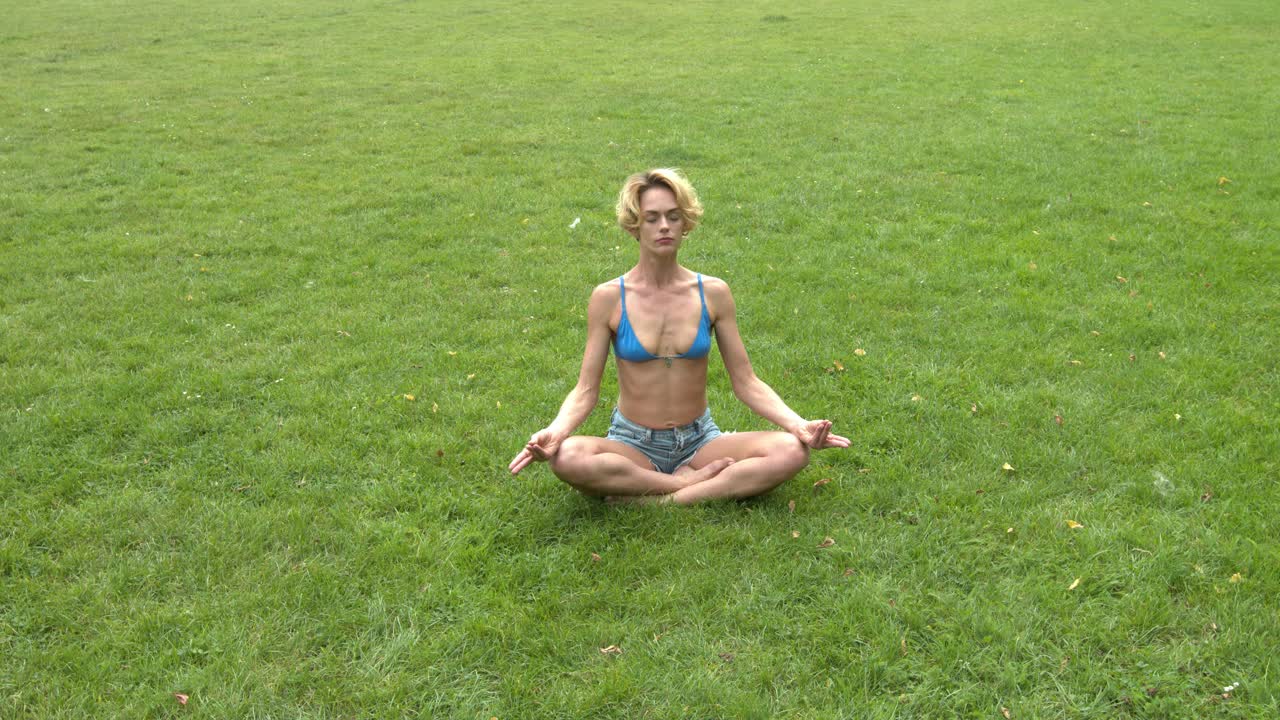 Mulher medita em parque tranquilo em postura de lótus de yoga