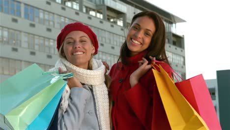 Pretty-girls-with-shopping-bags-smiling-at-the-camera