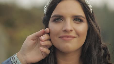 the face of the beautiful bride. the grooms hand gently caresses her cheek