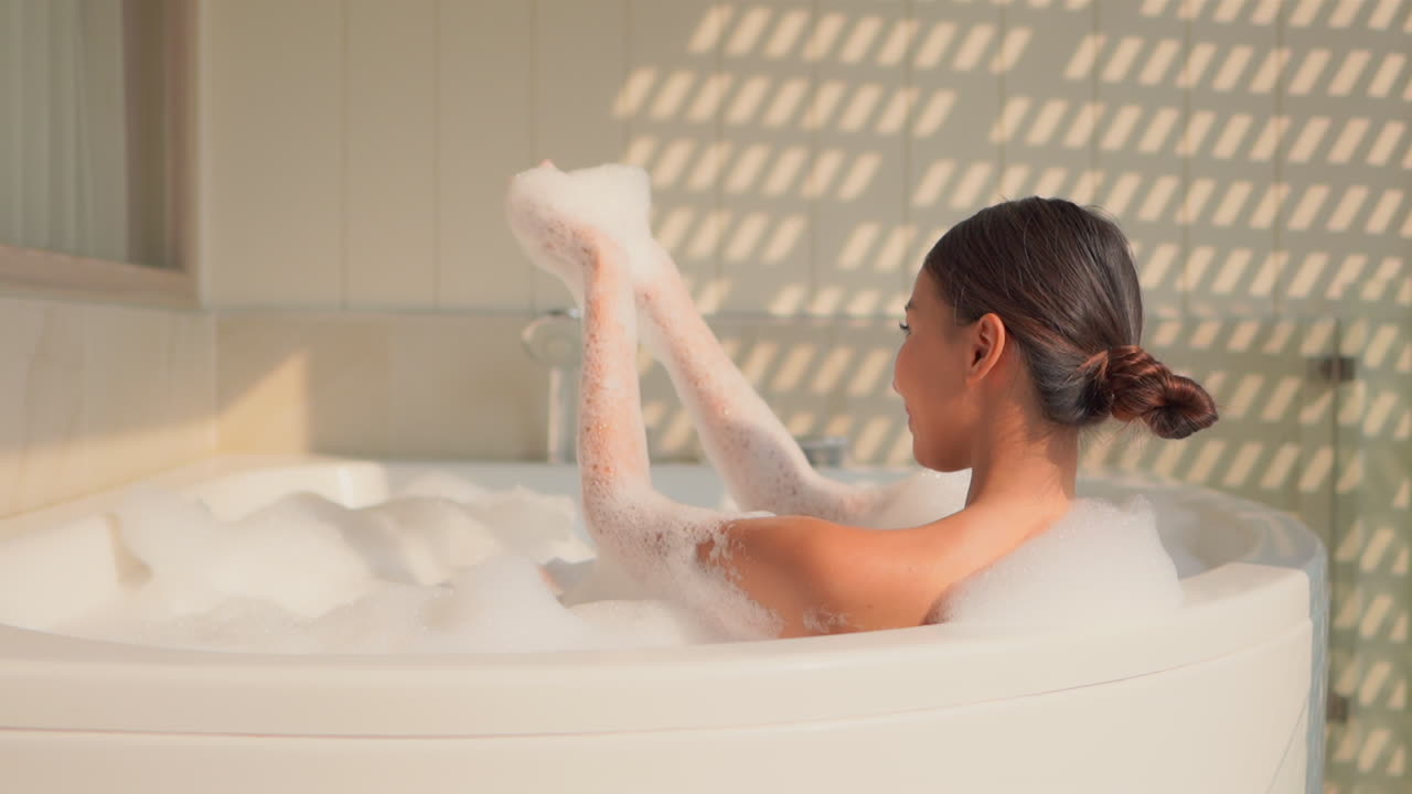 젊은 아시아인은 자유 시간을 즐기고 자쿠지에서 거품을 가지고 노는