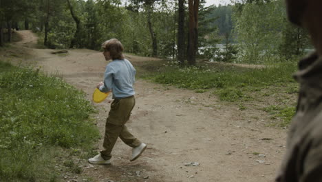 father and son playing frisbee in the woods