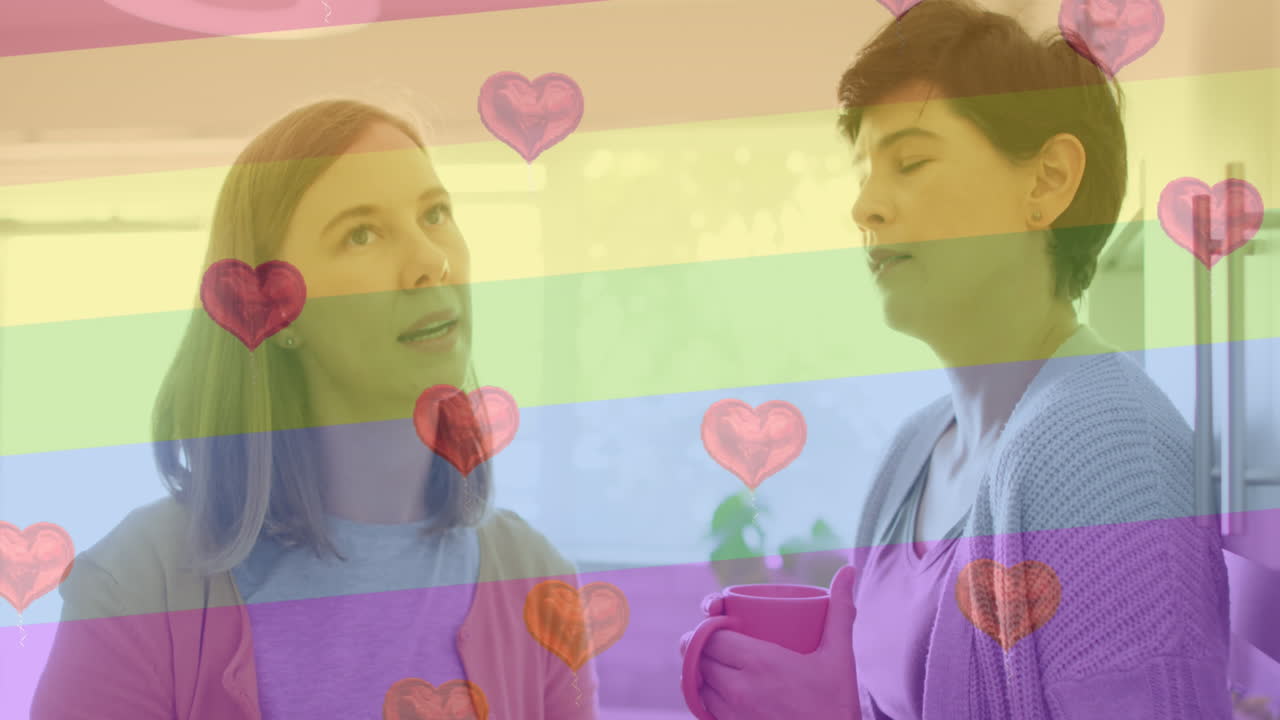 animación de emojis de corazón y bandera del arco iris sobre una pareja de mujeres caucásicas en casa